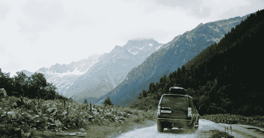 an SUV running along green hills and clear road, filled with road trip essentials