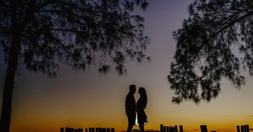a couple standing under a starry night close to each other.