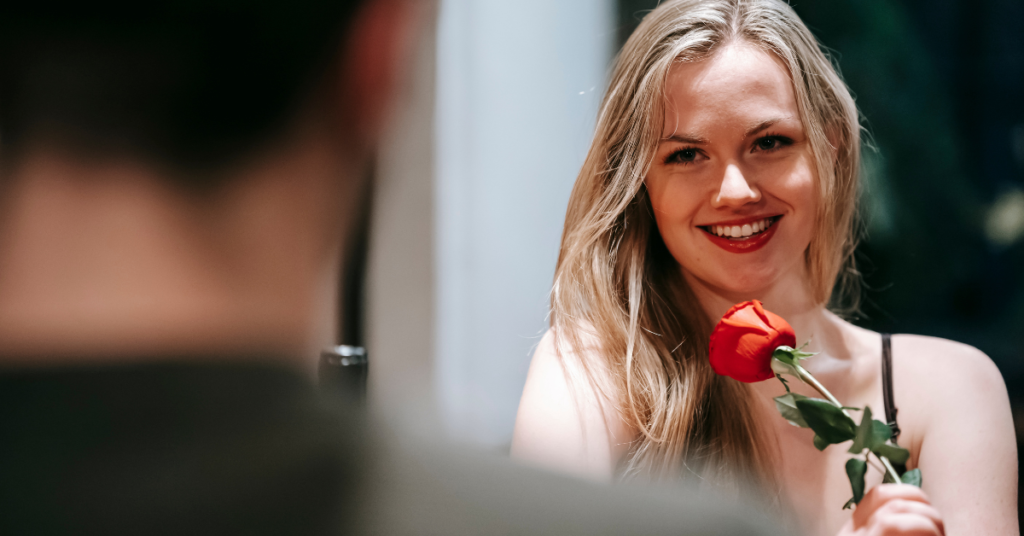 The image features a girl with a rose in hand, talking to a guy, on their first date.