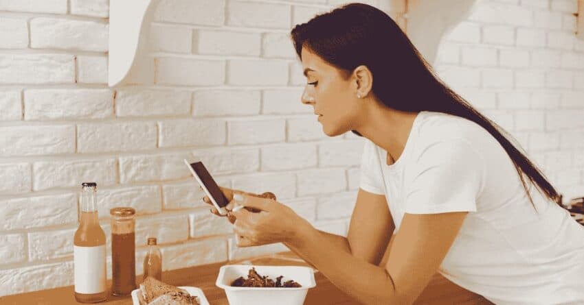 An image of a woman looking at her phone, to plan her intermittent fasting routine.