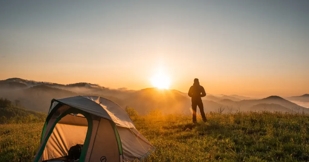 A solo camping traveler viewing the hills from a hillside.