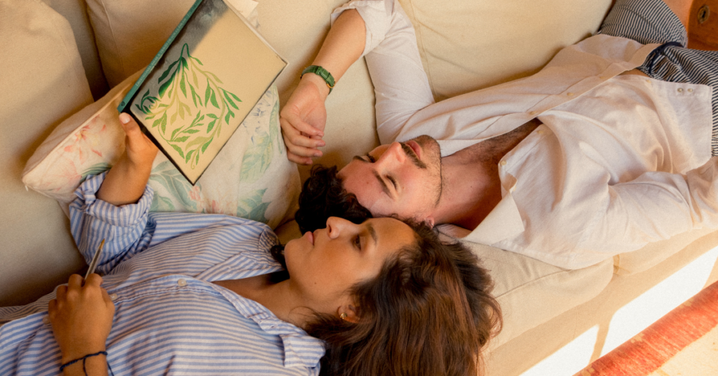 A couple, laying on a sofa with sad faces, to highlight the main theme of the blog- possible red flags in relationship. 